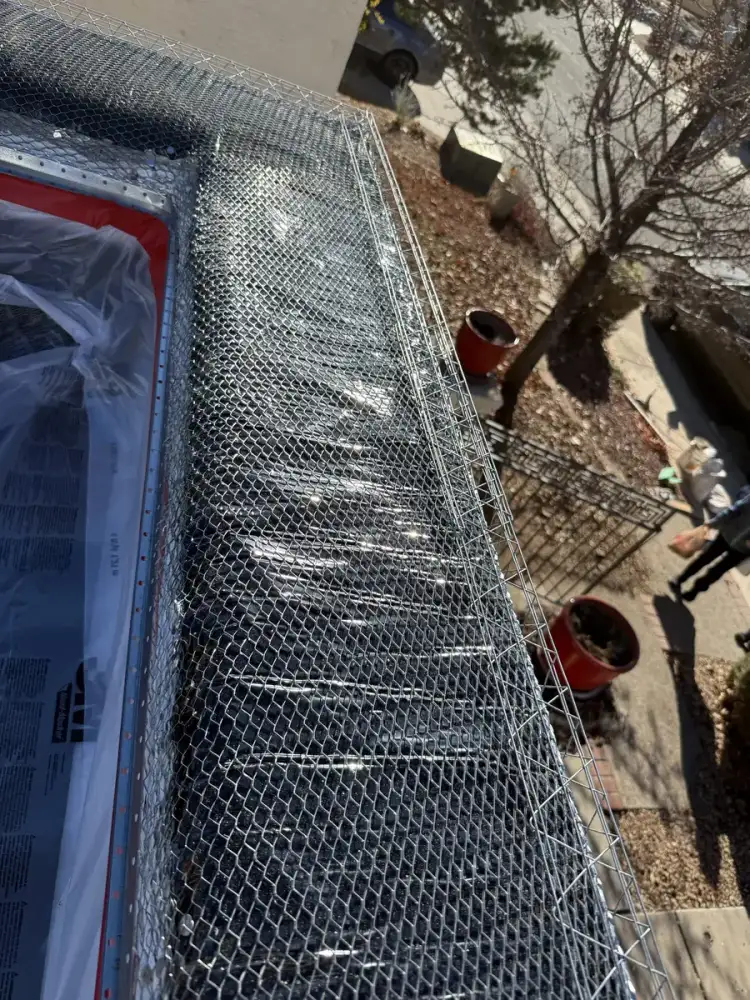 Metal lath fastened over building paper along the top of a wall, with the window below masked off in plastic.