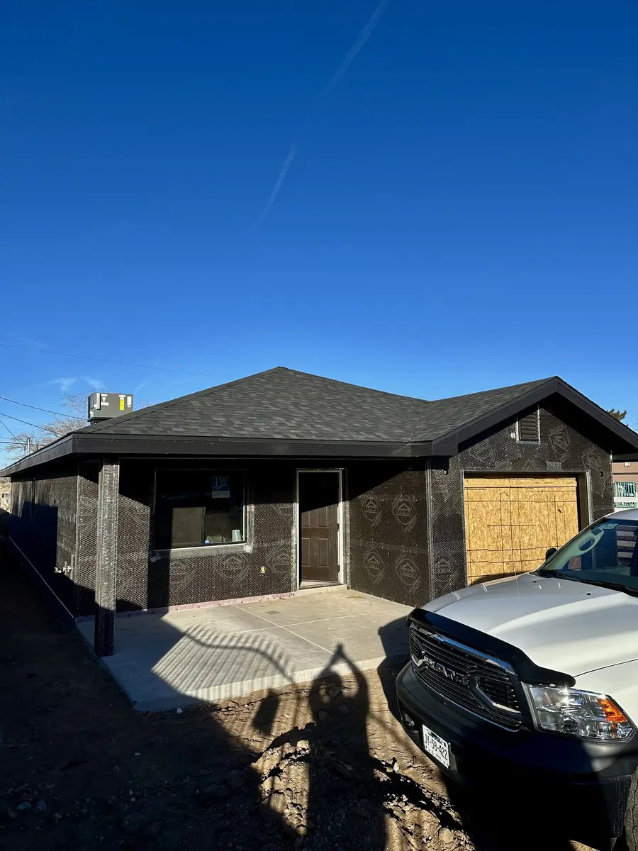 House wrapped in building paper and metal lath with the garage opening boarded, ready for the first coat of stucco.